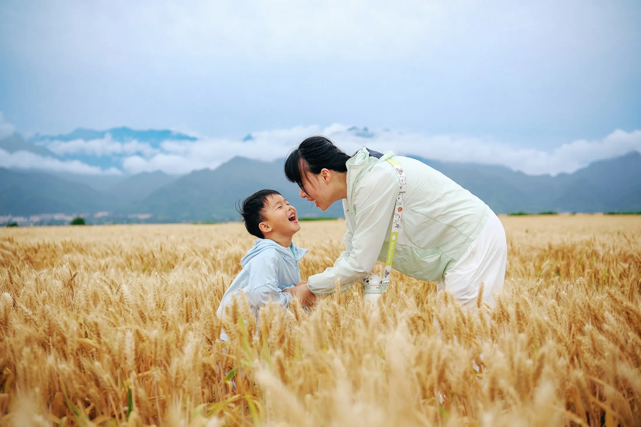 Mother and child laughing in a golden grass field