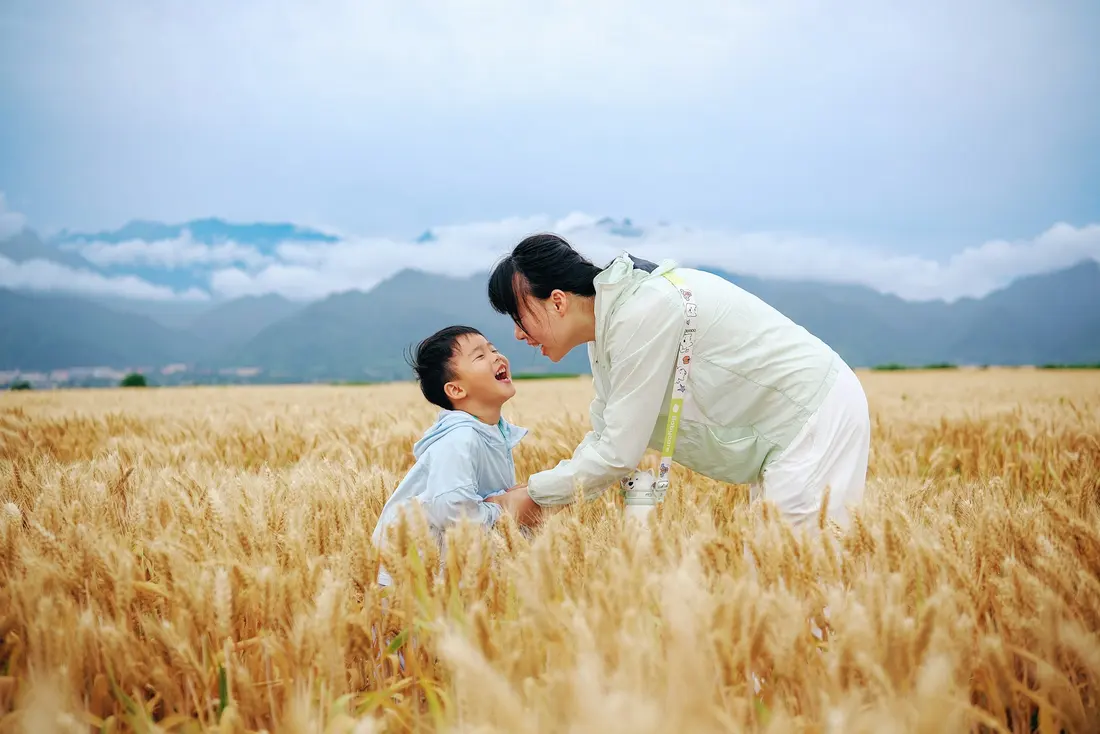 Mother and child laughing in a golden grass field